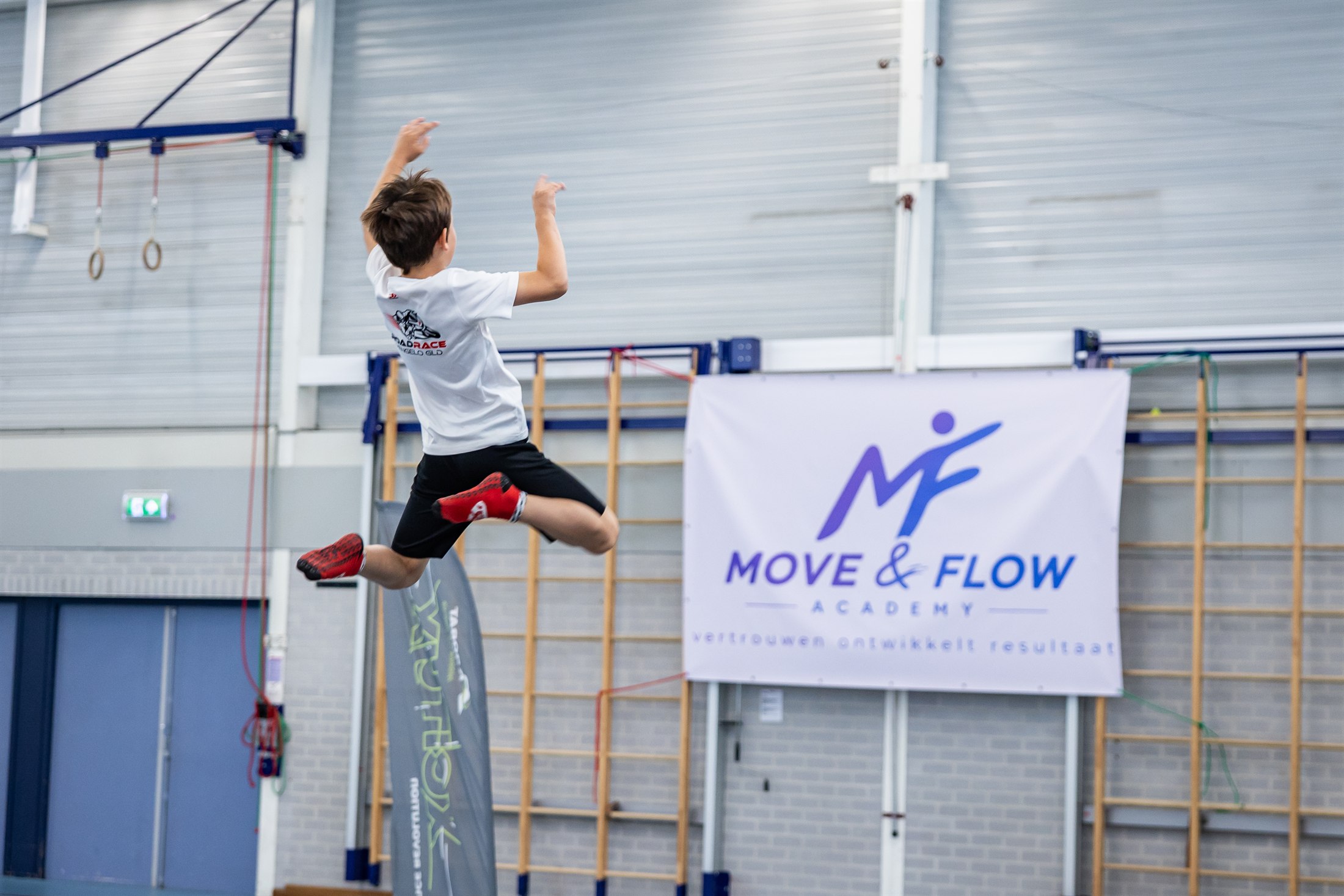 Kind maakt een freerunsprong in de zaal van Move & Flow Academy