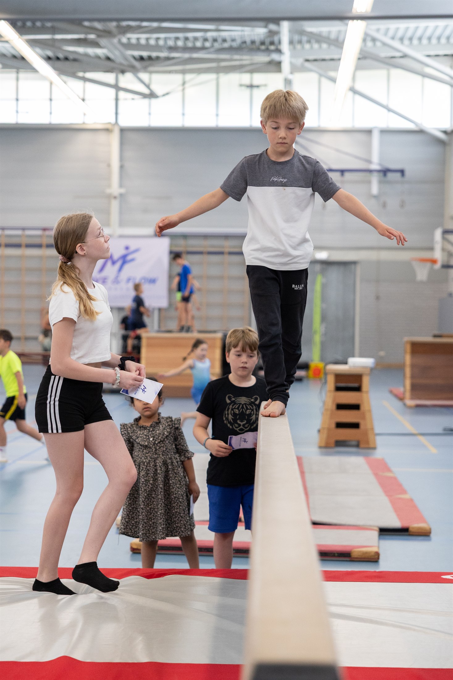 Kind oefent balans met persoonlijke begeleiding in de sportzaal